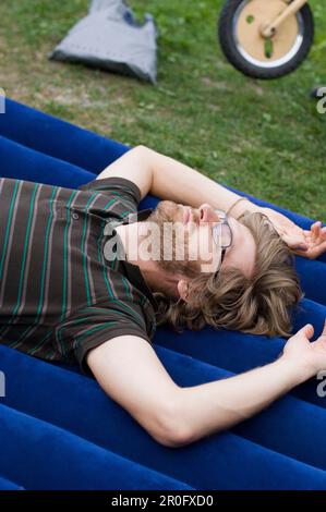 Mid adult man lying on airbed Stock Photo