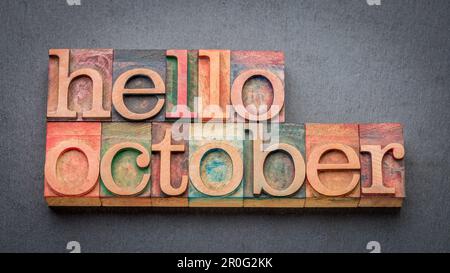 hello October greeting card - letterpress wood type blocks against gray slate stone Stock Photo