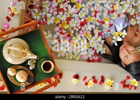 A woman bathing in a bath tub filled with blossoms, Spa of the Chedi Club, GHM Hotel, Ubud, Indonesia, Asia Stock Photo
