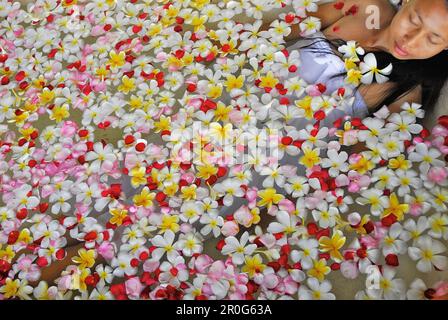 A woman bathing in a bath tub filled with blossoms, Spa of the Chedi Club, GHM Hotel, Ubud, Indonesia, Asia Stock Photo