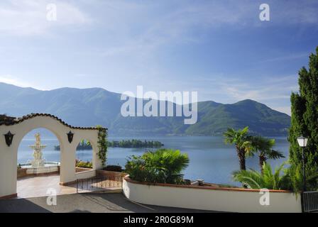 Entrance of hotel with fountain and palm trees at lake Maggiore with isle of Brissago, Isole di Brissago, Ronco sopra Ascona, lake Maggiore, Lago Magg Stock Photo