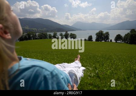 Young woman lying in the grass, near lake Tegernsee, Upper Bavaria, Bavaria, Germany Stock Photo