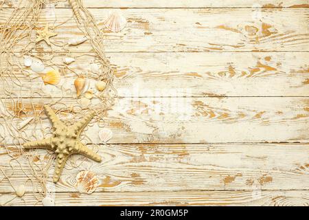Beautiful starfish with seashells and net on light wooden background Stock Photo