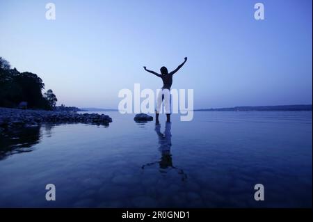 Young woman standing in shallow water, Lake Constance, Baden-Wurttemberg, Germany Stock Photo