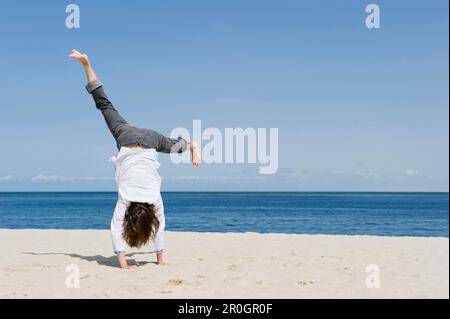 Woman turning cartwheels on sandy beach, List, Sylt, Schleswig-Holstein, Germany Stock Photo