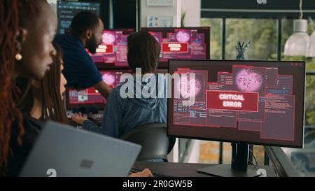 Team of system engineers having web server hacked, reading critical error on multiple monitors in office. Diverse software developers trying to solve hacking problem, firewall security. Stock Photo
