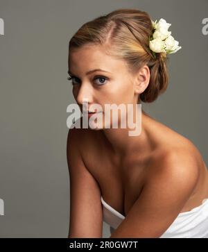 Expressing timeless style and elegance. Studio portrait of an attractive young woman with a flower in her hair. Stock Photo