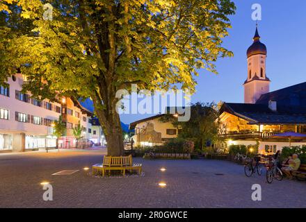 Tree witzh illuminated church in Garmisch-Partenkirchen, Bavaria, Germany Stock Photo