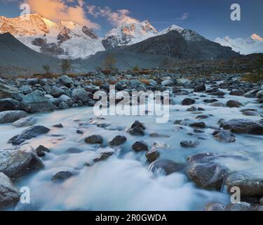 Stony river in front of snow covered mountains in the evening sun, Val Roseg, Piz Bernina, Piz Roseg, Grisons, Switzerland, Europe Stock Photo