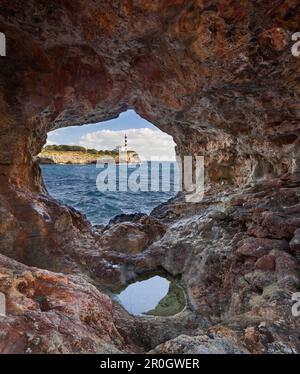 View through hole in a rock onto lighthouse of Portocolom, Punta de s'Homonet, East Coast, Mallorca, Spain, Europe Stock Photo