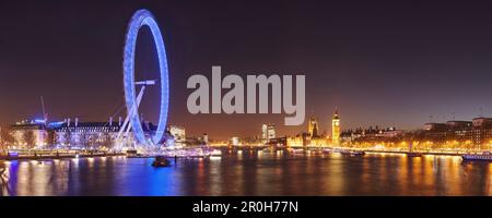 Panorama of the City of London with view from the Hungerford Bridge over the Thames towards the London Eye, Big Ben and Westminster Palace at night, E Stock Photo