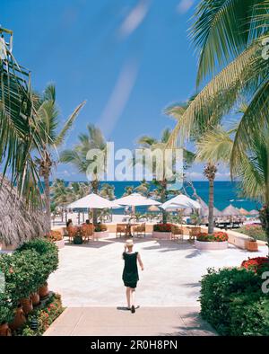 MEXICO, two women sitting under canopy with one woman walking in foreground at in Four Seasons Resort Stock Photo