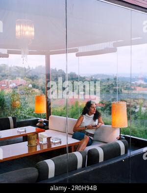 TURKEY, Istanbul, mid adult female looking away while sitting in Ulus 29 Restaurant Stock Photo