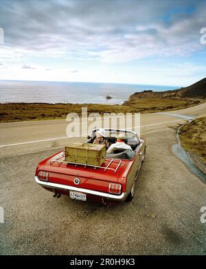 USA, California, Big Sur, couple on a road trip in a 1965 Ford Mustang, Hwy 1 Stock Photo