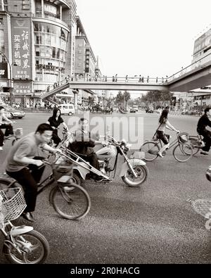 CHINA, Hangzhou, people riding bicycles and motorcycles in an urban area (B&W) Stock Photo