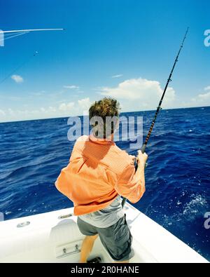 USA, Florida, man reeling in a fish at sea, rear view, Islamorada Stock Photo