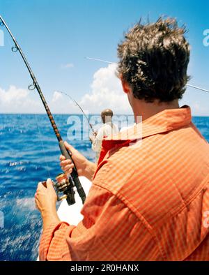 Two Fishing Rods Held In Fishing Rod Holders Attached To A Back Of A Boat  The Rods Are Bent From The Weight Of The Down Riggers People Are Trolling  For Salmon Of