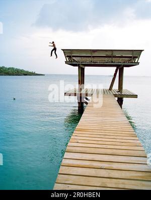 HONDURAS, Roatan, boy jumping off pier to get his soccer ball Stock Photo