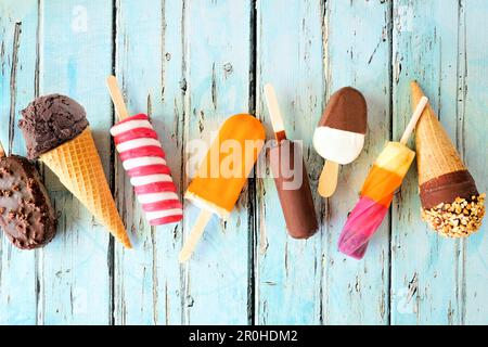 Variety of chocolate and colorful summer popsicles and ice cream treats. Top view scattered on a rustic blue background. Stock Photo