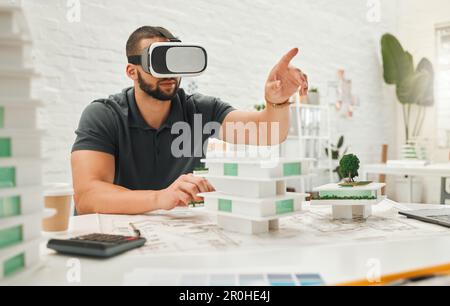 Young businessman playing with a VR headset. Architect playing a game on AI goggles. Young engineer pointing while using virtual reality headset Stock Photo
