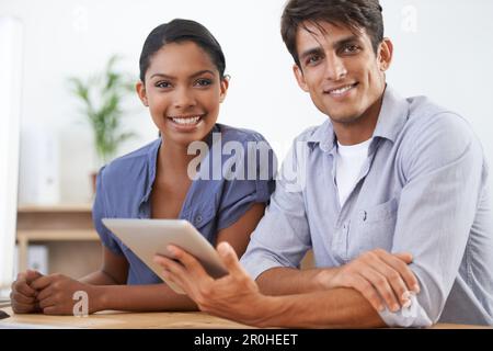 Well get any job done...together. two young colleagues using a digital tablet. Stock Photo