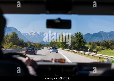 View through a windshield on freeway A95 with Wetterstein mountain rainge in background, Bavaria, Germany Stock Photo