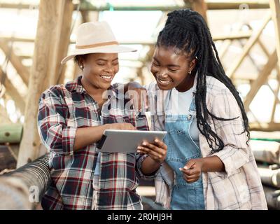 Two farmers using a digital device. Happy farmers talking. Two colleagues collaborating in a garden. Farm workers in a nursery online on a digital Stock Photo
