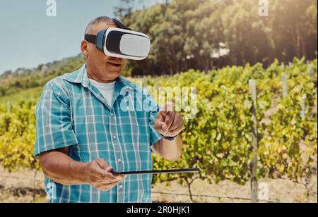 One senior mixed race farmer using virtual reality headset and digital tablet. Hispanic elderly man using technology to browse through metaverse. Old Stock Photo
