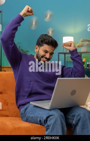 Oh my God Wow. Surprised indian man using laptop computer, receive good news message, shocked by sudden victory, celebrate lottery jackpot win purchases online shopping at home. Lifestyle technologies Stock Photo