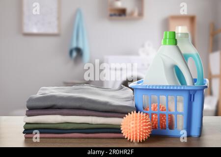 Dryer balls, detergents and stacked clean clothes on wooden table in laundry room Stock Photo