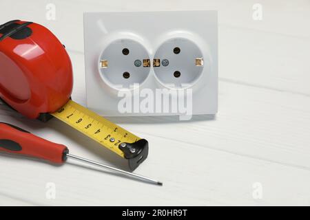 Power socket and set of electrician's tools on white wooden table, closeup Stock Photo