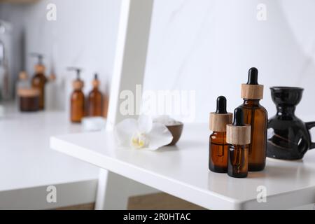 Bottles of essential oil on white shelf in bathroom. Space for text Stock Photo