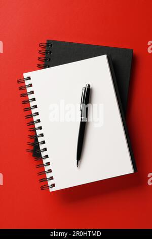 Notebooks and pen on red background, top view Stock Photo