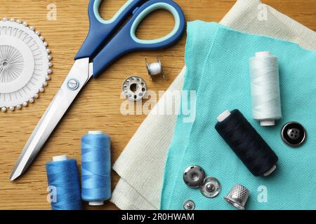 Flat lay composition with spools of threads and sewing tools on wooden table Stock Photo
