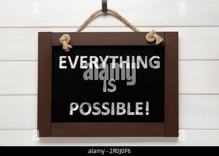 Small chalkboard with motivational quote Everything is possible hanging on white wooden wall Stock Photo