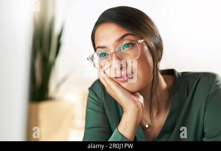 Its such a boring day. a young businesswoman staring at her PC screen in boredom. Stock Photo