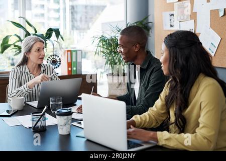 First came the hurricane, then the morning sun. a group of businesspeople brainstorming and using a laptop in a modern office. Stock Photo