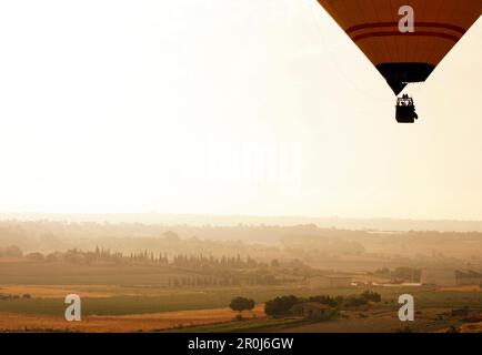 A hot air balloon rising from a field at sunrise, near Manacor, Mallorca, Balearic Islands, Spain, Europe Stock Photo