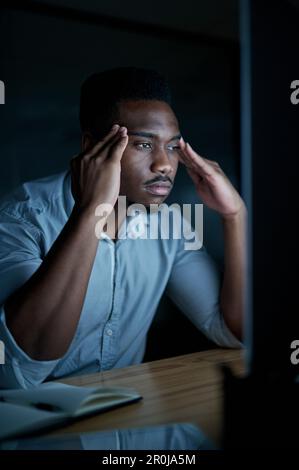 Why give up when you can give it all youve got. a young businessman looking stressed while using a computer during a late night at work. Stock Photo