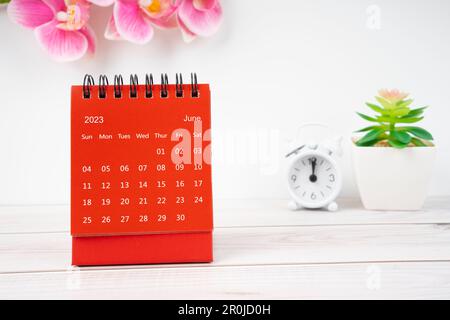 Red calendar June 2023. Desk calendar for year 2023 and pink orchid on wooden background. Stock Photo