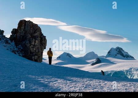 Chinstrap penguin (Pygoscelis antarctica) in dramatic landscape with person looking on, Half Moon Island, South Shetland Islands, Antarctica Stock Photo