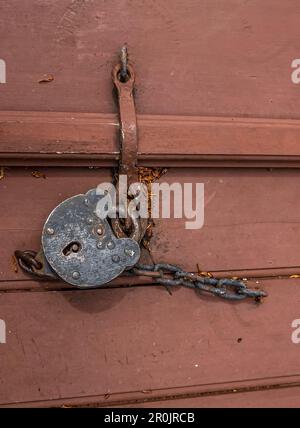Rustic metal lock with chain on a red wooden door Stock Photo