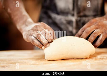 Meeting all your kneads. a male baker busy shaping dough at work. Stock Photo