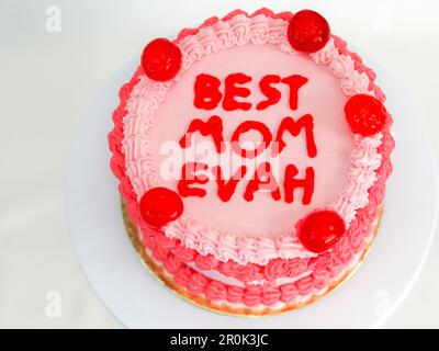 frosted pink red cake for mothers day celebration with funny text topping best mom evah on white studio background Stock Photo