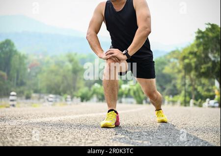 Cropped image, A sporty Asian man in sportswear stretching his legs, doing lunges, getting ready for running in a park. Stock Photo