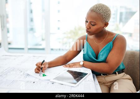 Giving every design all shes got. a young woman going over blueprints in a modern office. Stock Photo