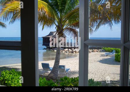 Palm trees and overwater spa cabana of Half Moon Resort seen through window of Royal Suite in Royal Court accomodation Rose Hall, near Montego Bay, Sa Stock Photo
