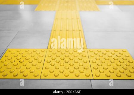 Top view of yellow tactile tiles for the blind stacked on gray tiled floor Stock Photo