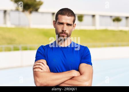 Confident in my athletic ability. Cropped portrait of a handsome young male athlete standing with his arms folded on the track. Stock Photo