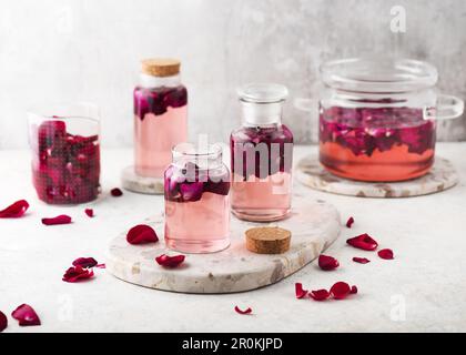 Homemade petal rose water or syrup in glass bottles made for preparing of cocktails, drinks, lemonade or sweet desserts. Healthy summer food concept. Stock Photo
